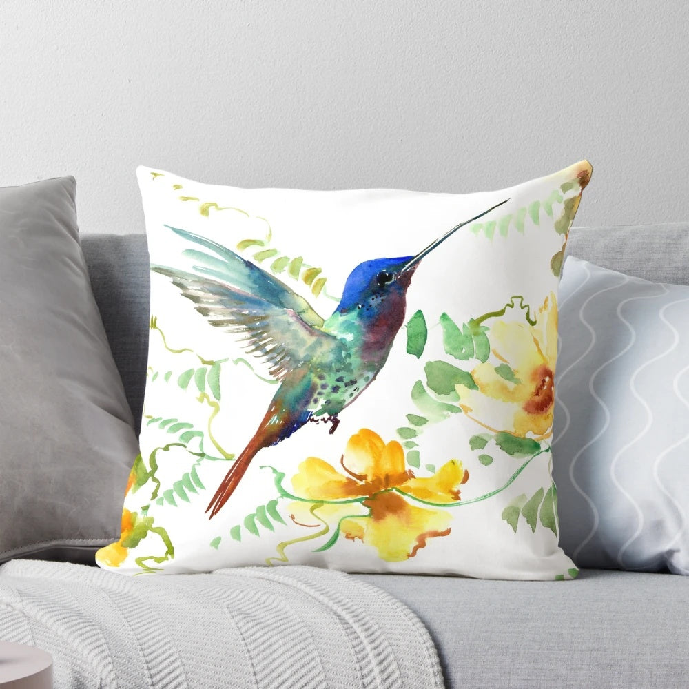A vibrant watercolor painting of a hummingbird hovering above tropical flowers on a decorative accent pillow.