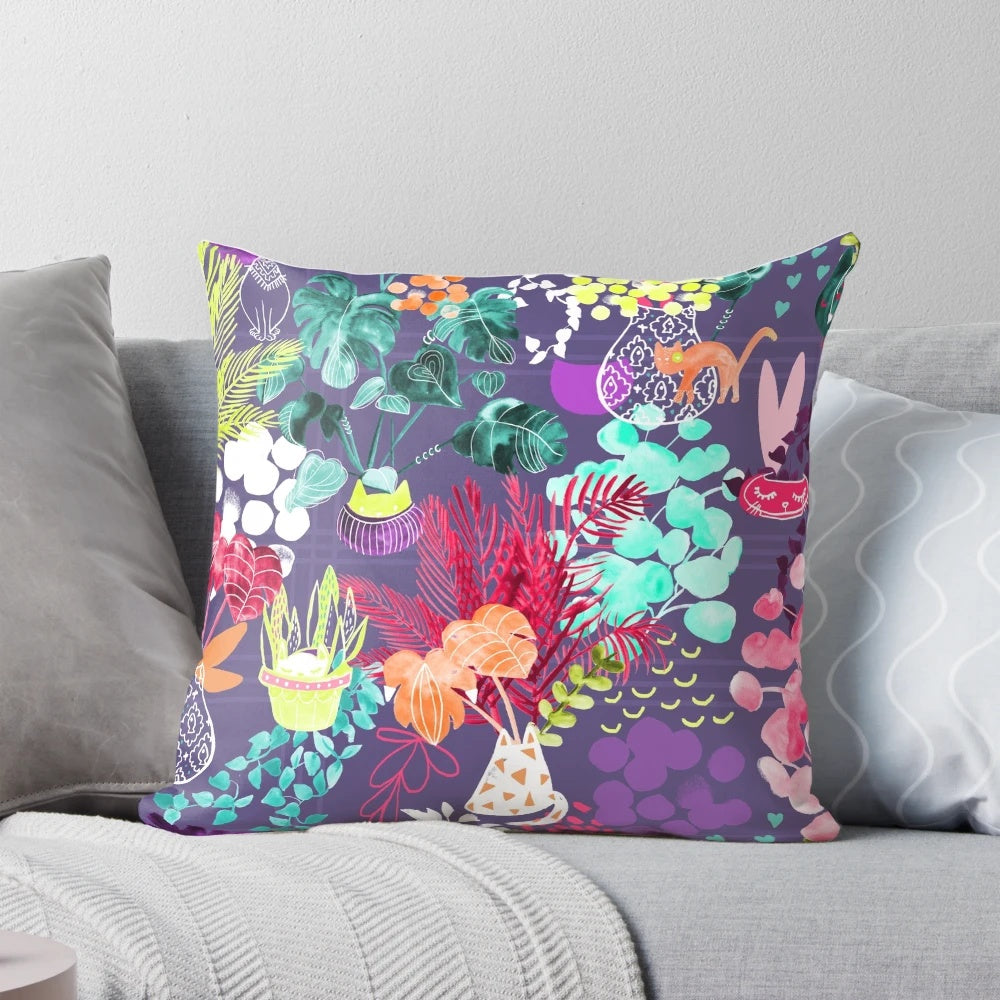 A colorful and modern pillow featuring a watercolor-style illustration of indoor plants, kittens, and a geometric design in shades of teal, pink, purple, and green.