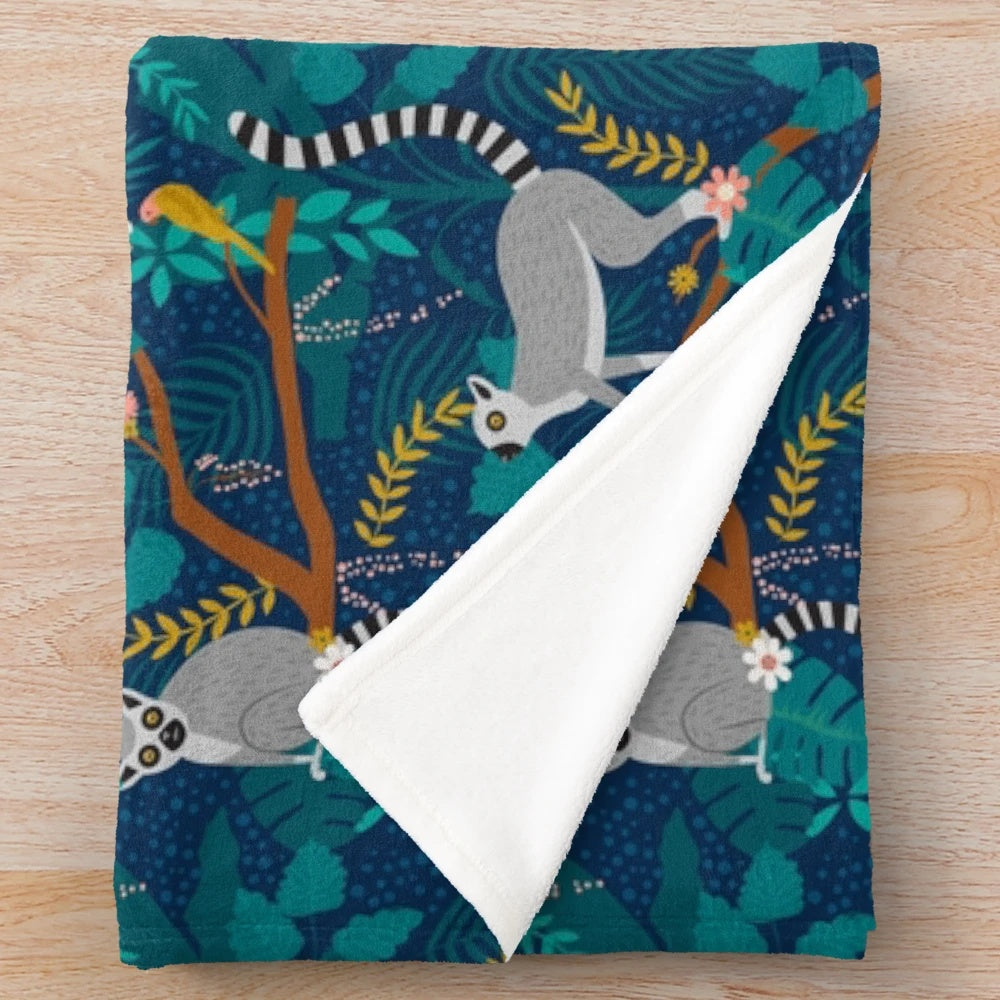 A soft and cozy plush blanket featuring a vibrant design of lemurs in a lush, tropical jungle.
