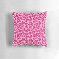 A plush, rectangular pillow with a modern leopard print design in shades of pink and fuchsia.