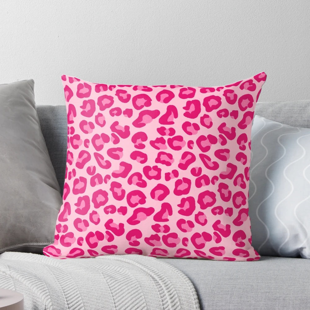 A plush, rectangular pillow with a modern leopard print design in shades of pink and fuchsia.