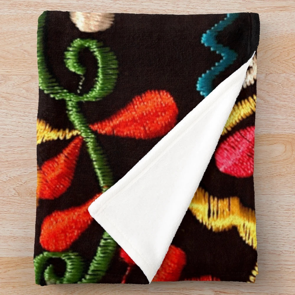 Colorful plush blanket featuring a design of butterflies and a red flower, representing Mexican art and design