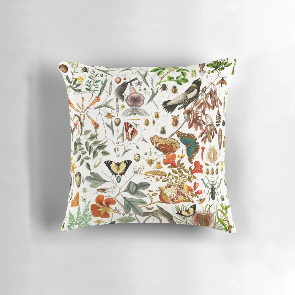 Closeup of a vibrant nature-inspired throw pillow featuring detailed illustrations of butterflies, birds, and flowers.