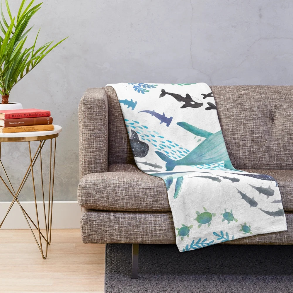 Colorful plush blanket featuring watercolor designs of ocean animals including whales, sharks, and sea turtles