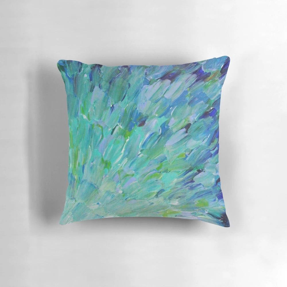 Decorative pillow featuring an abstract design with peacock feathers, mermaid fins, and ocean waves in shades of teal, navy, and avocado green.