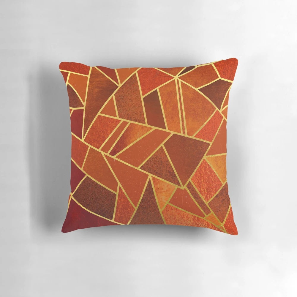 Close-up of an orange and emerald green decorative throw pillow with geometric patterns and gold lines.
