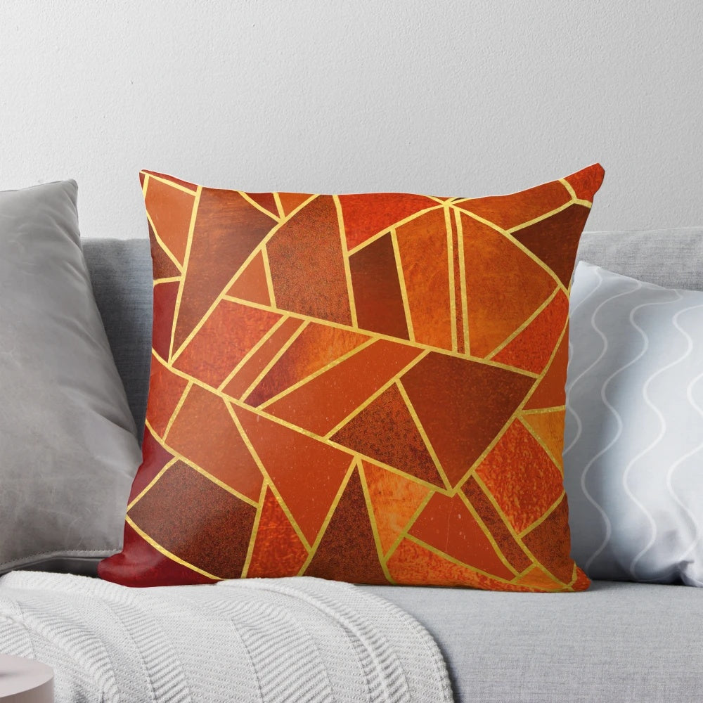 Close-up of an orange and emerald green decorative throw pillow with geometric patterns and gold lines.