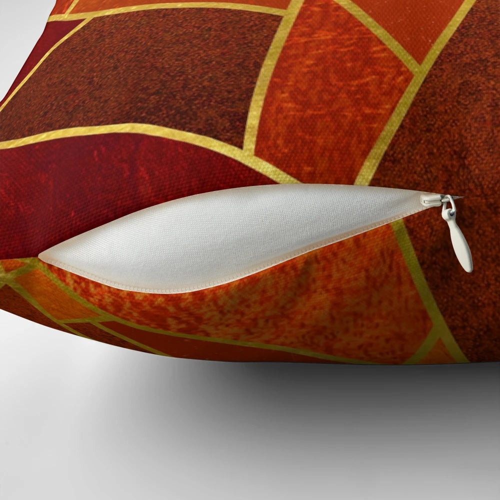 Close-up of an orange and emerald green decorative throw pillow with geometric patterns and gold lines.