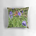 A decorative pillow featuring a vibrant peacock butterfly perched on a bed of blooming bluebells in a lush, wild woodland scene.