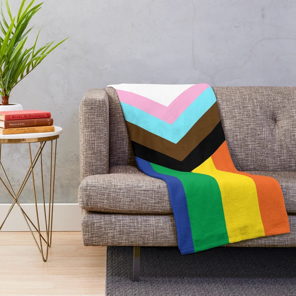 Plush blanket in the colors of the progress pride flag, representing LGBTQIA+ diversity and inclusion.