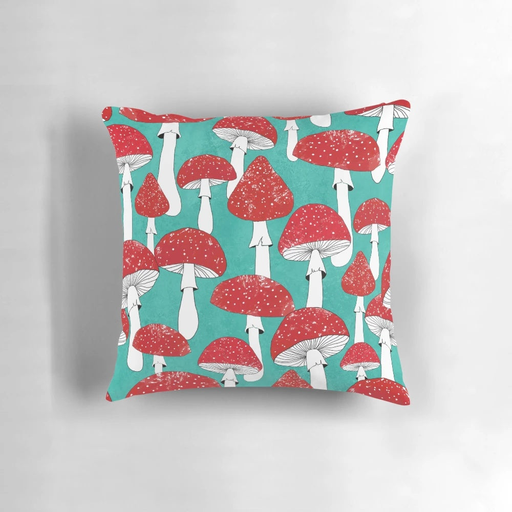 Artistic illustration of red mushrooms on a turquoise blue background, featured on a decorative pillow.