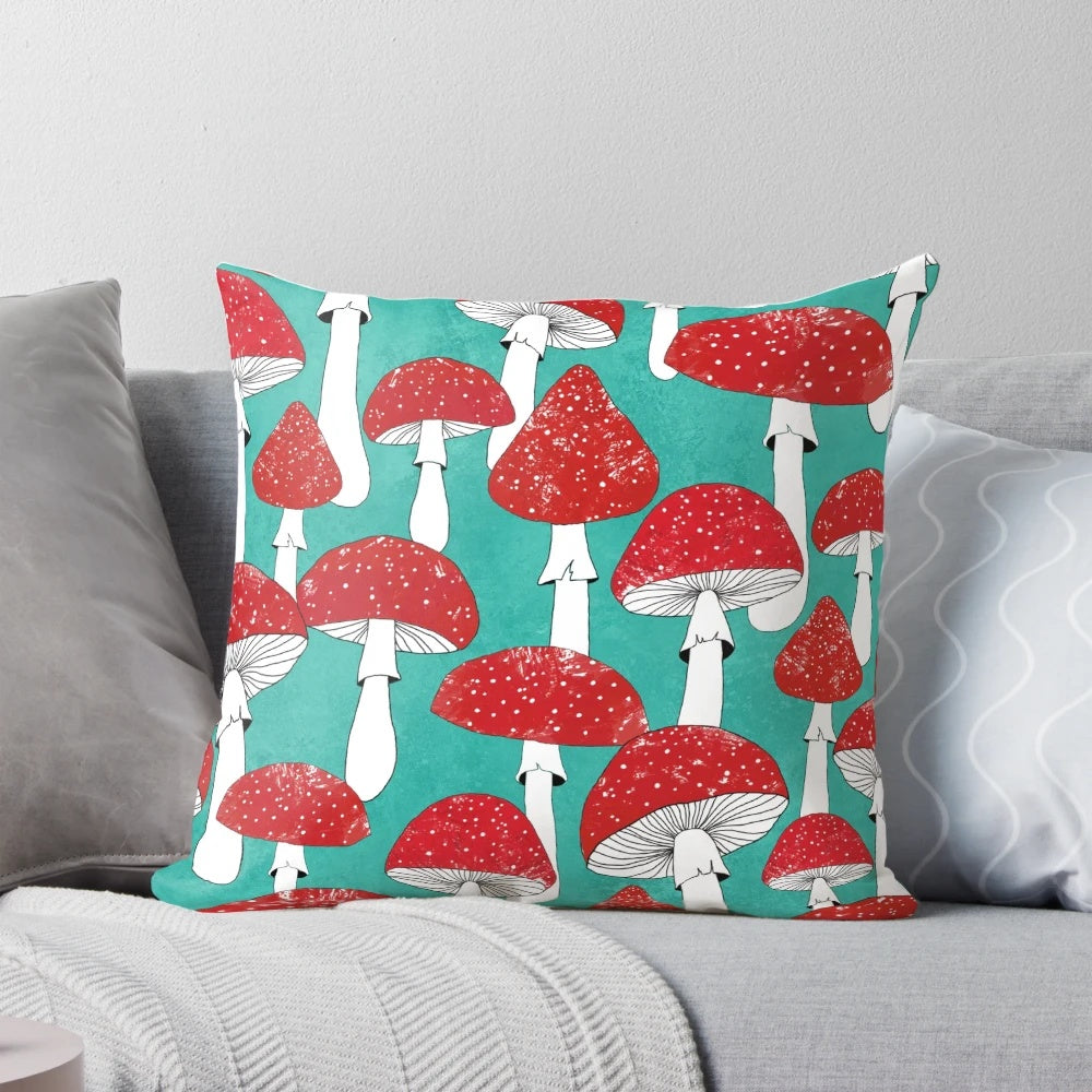 Artistic illustration of red mushrooms on a turquoise blue background, featured on a decorative pillow.