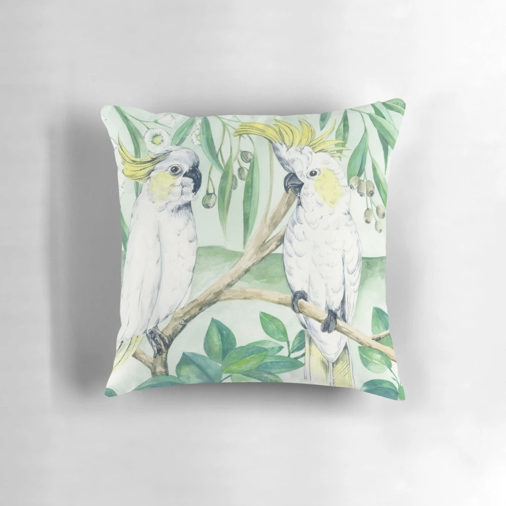 Colorful saffron cockatoos perched on a branch against a green and yellow background on a throw pillow