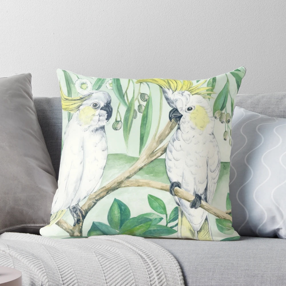 Colorful saffron cockatoos perched on a branch against a green and yellow background on a throw pillow