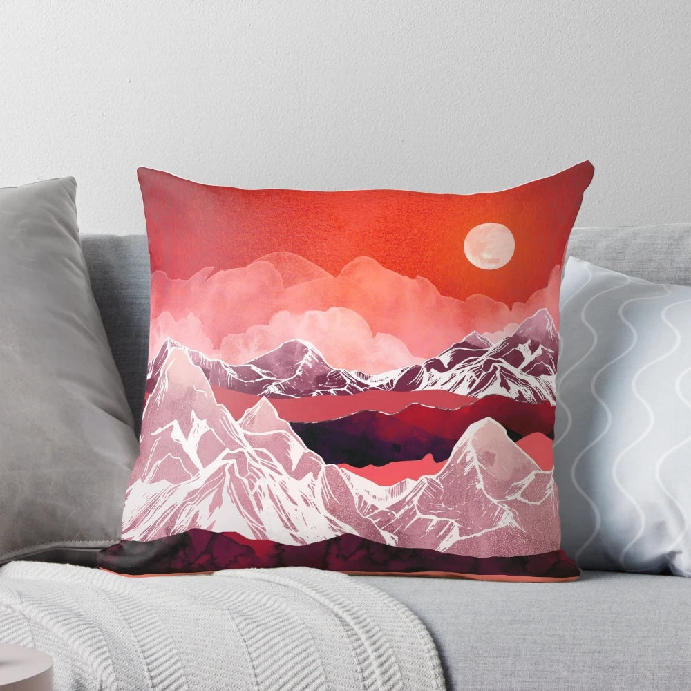 Scarlet, pink, and purple watercolor painting of a mountain landscape on a decorative throw pillow