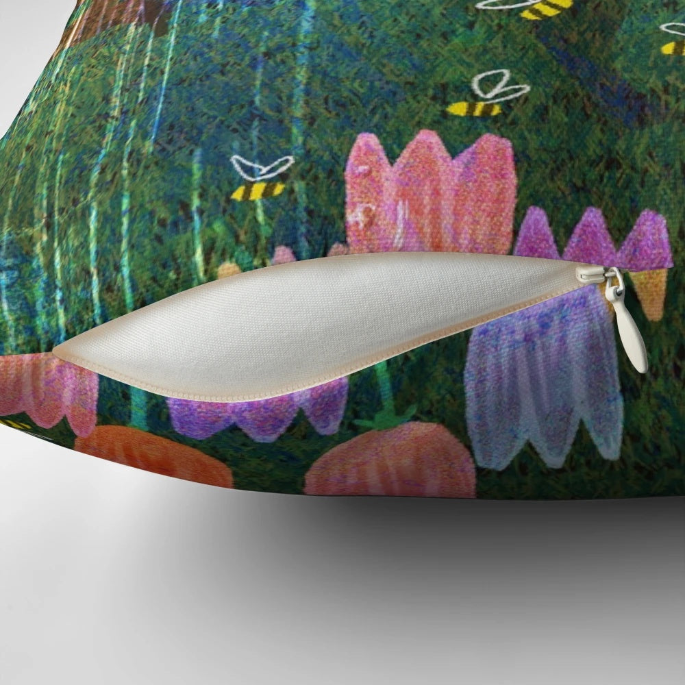 A colorful spring-themed pillow featuring bunnies, flowers, and a rainbow against a lush, green background.