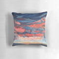 A beautiful throw pillow featuring a vibrant sunset seascape design with indigo, coral, and navy accents.