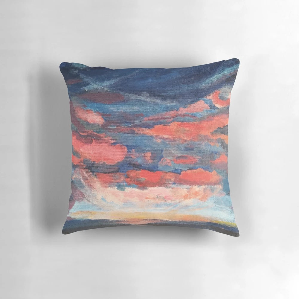 A beautiful throw pillow featuring a vibrant sunset seascape design with indigo, coral, and navy accents.