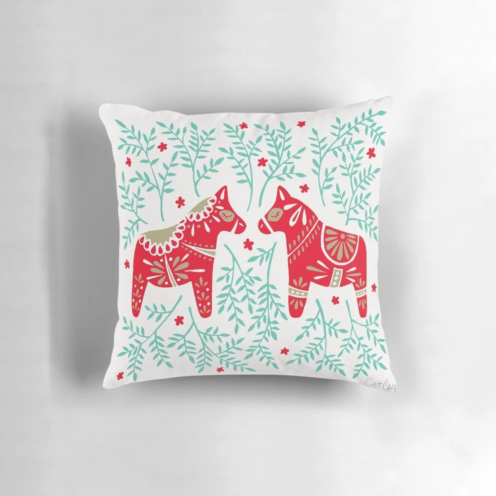 Decorative throw pillow featuring a pair of red and mint Swedish Dala horses against a symmetrical leaf pattern.
