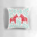 Decorative throw pillow featuring a pair of red and mint Swedish Dala horses against a symmetrical leaf pattern.