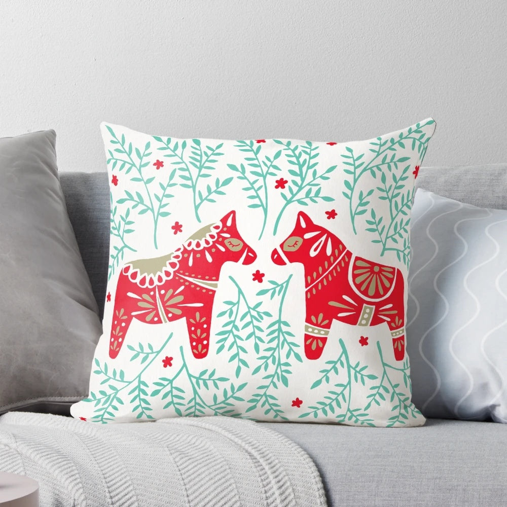 Decorative throw pillow featuring a pair of red and mint Swedish Dala horses against a symmetrical leaf pattern.