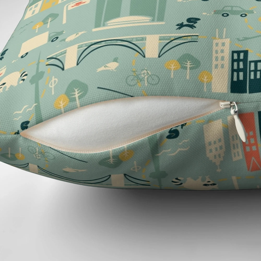 Decorative square pillow featuring a vibrant cityscape of Toronto's iconic buildings, buses, and streetcars.