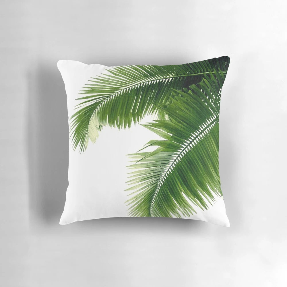 Decorative throw pillow featuring a watercolor design of lush, tropical palm leaves and greenery.