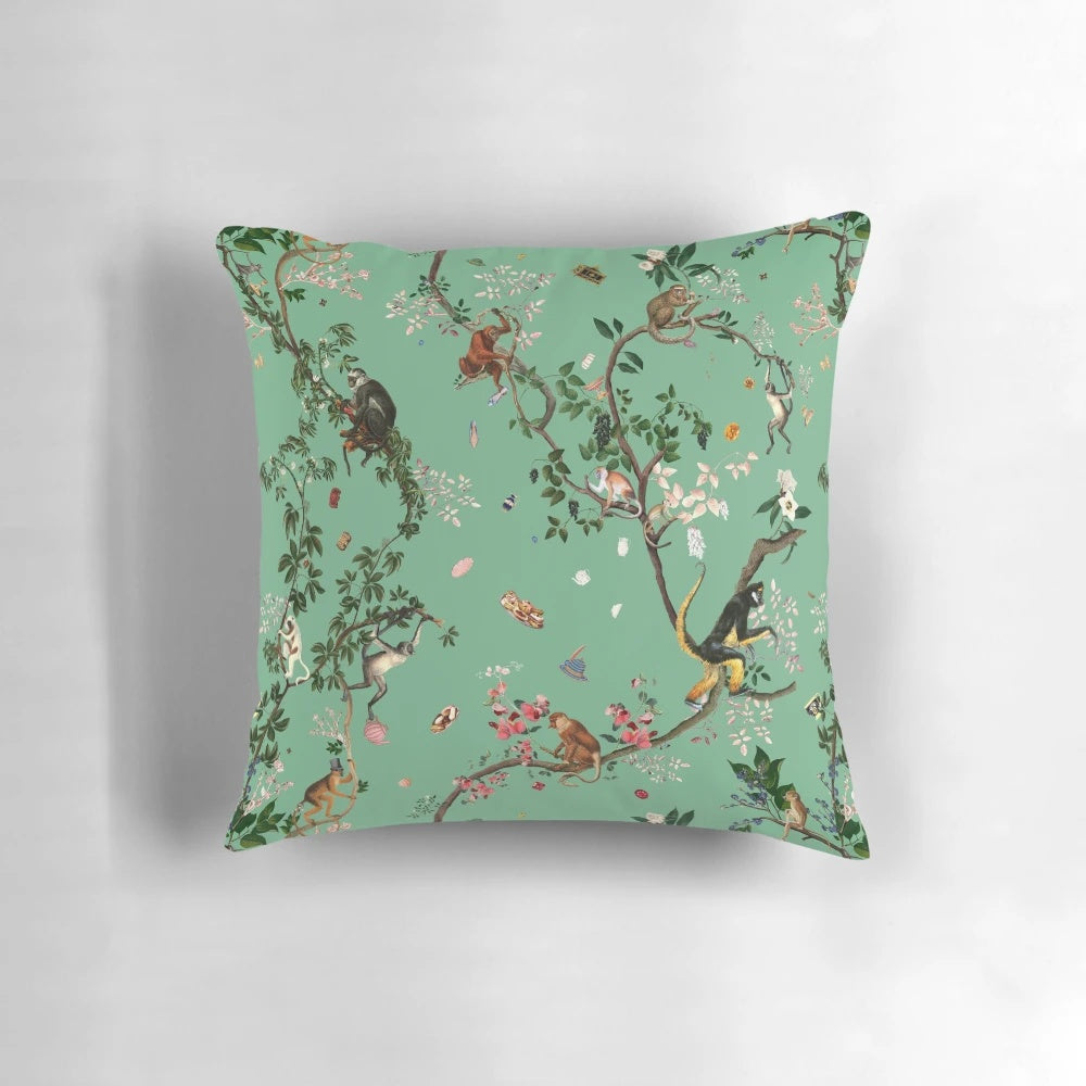 A lush, green pillow featuring a playful monkey design amidst a botanical, floral jungle pattern.