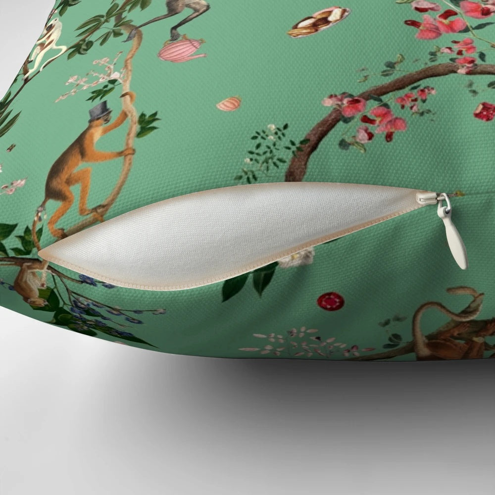 A lush, green pillow featuring a playful monkey design amidst a botanical, floral jungle pattern.