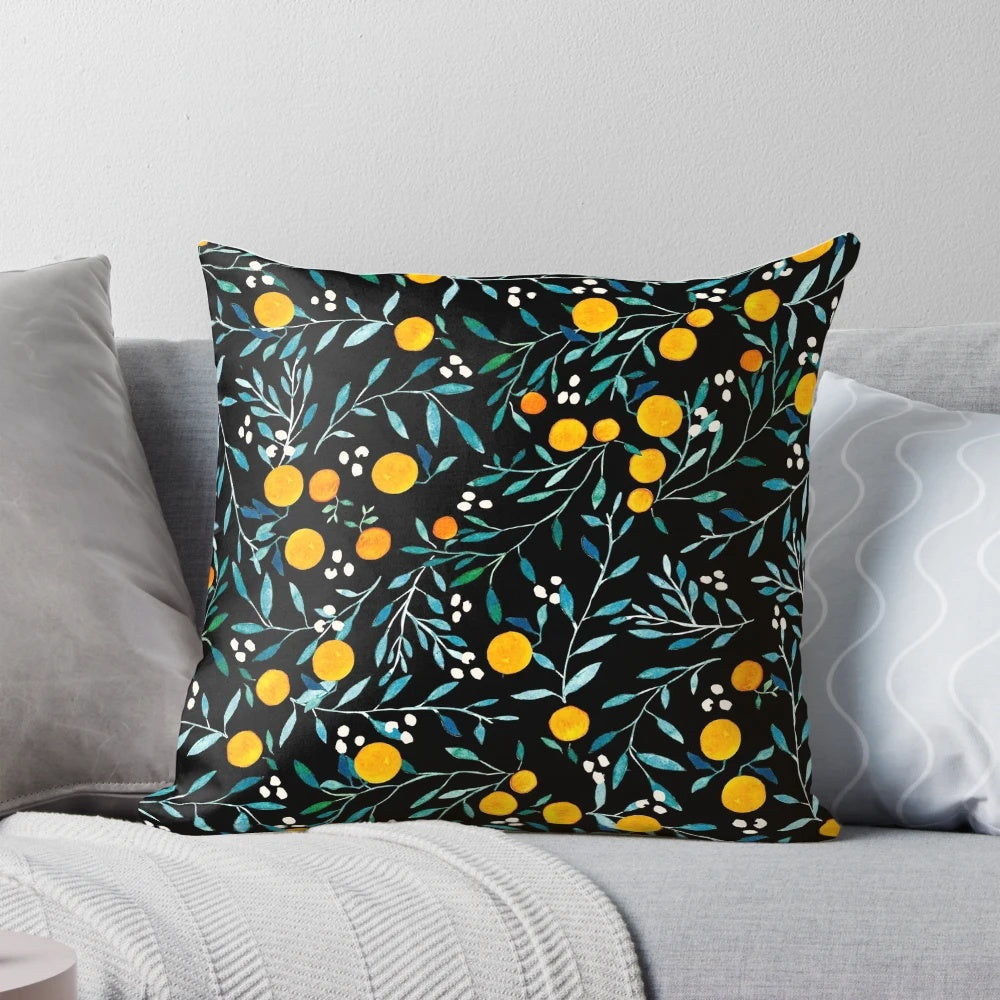 Pillow featuring a vibrant watercolor pattern of oranges and floral elements on a black background