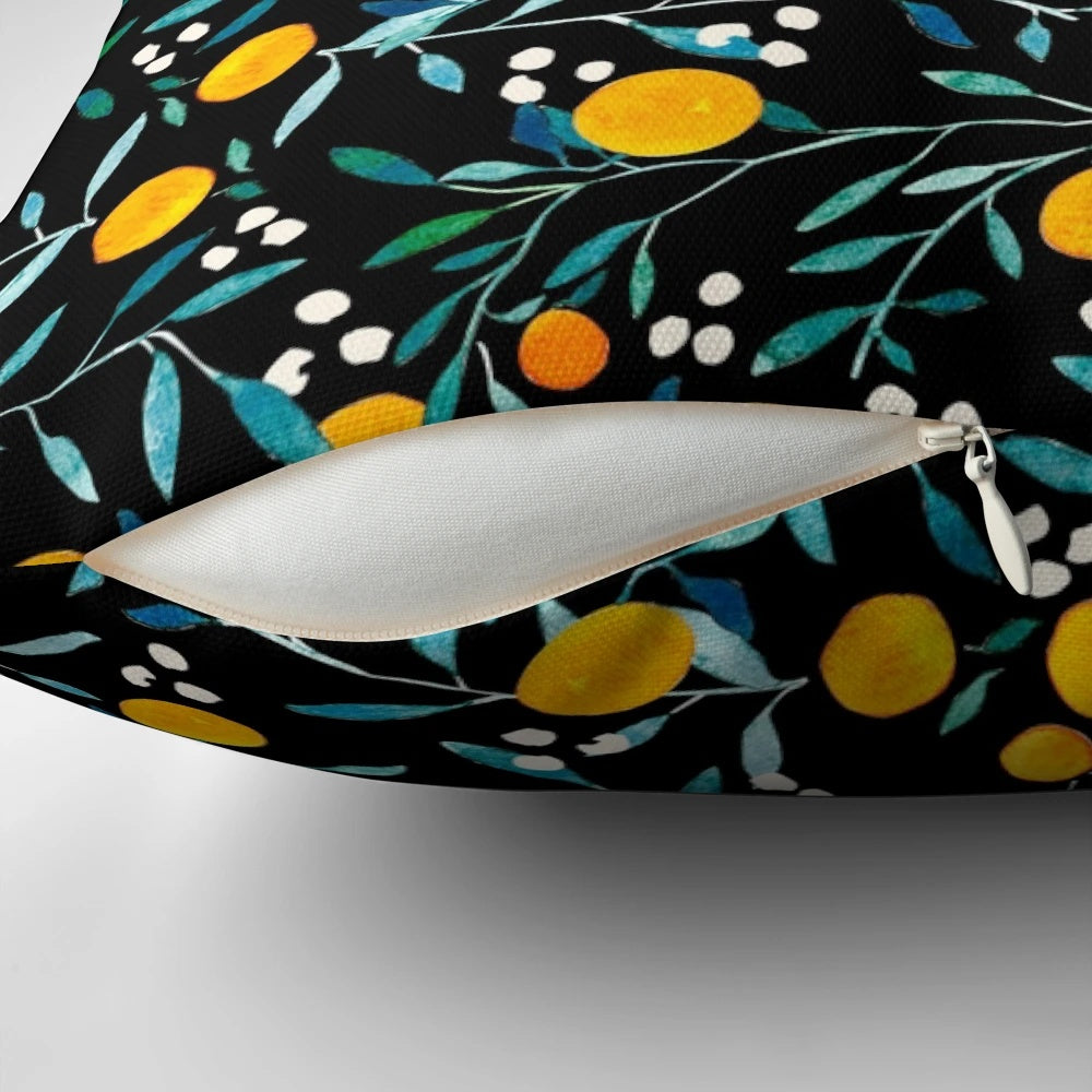 Pillow featuring a vibrant watercolor pattern of oranges and floral elements on a black background