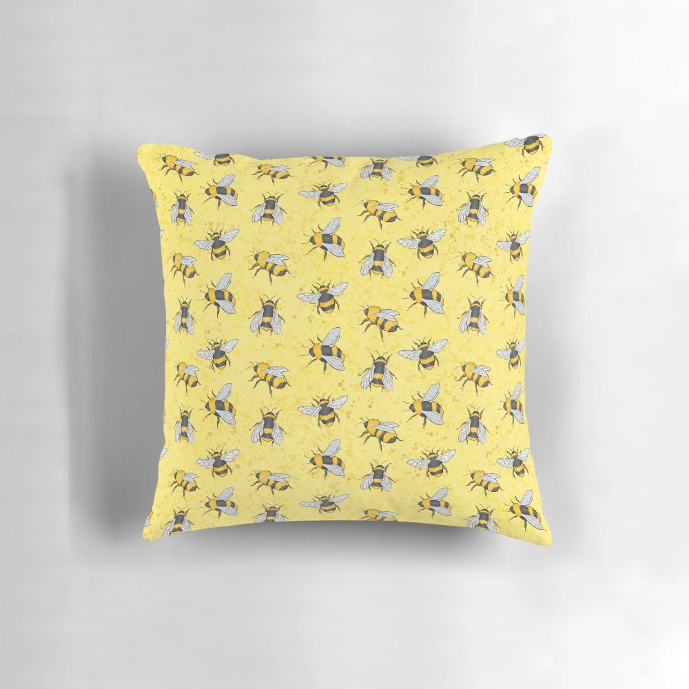 A yellow and black patterned pillow featuring a repeating bumble bee design