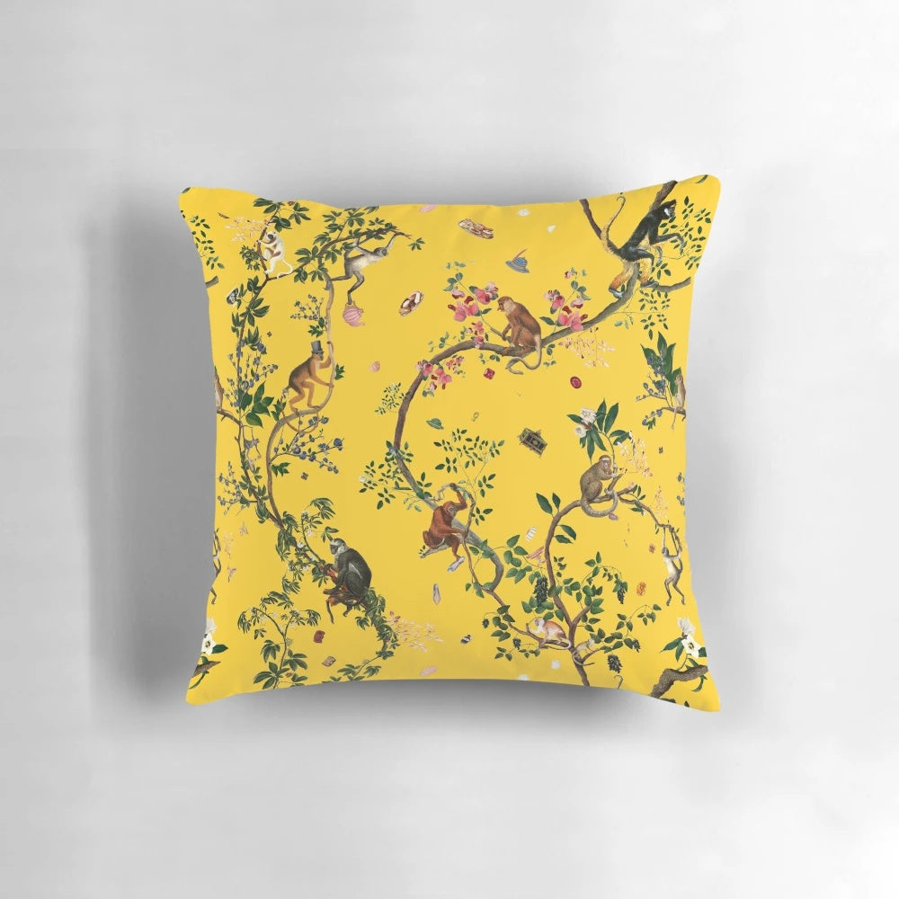 Closeup of a yellow pillow with a vibrant monkey and floral design, perfect for tropical-themed home decor.