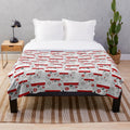 Vintage caravan-inspired plush blanket in red, white, and grey colors with a repeat pattern design