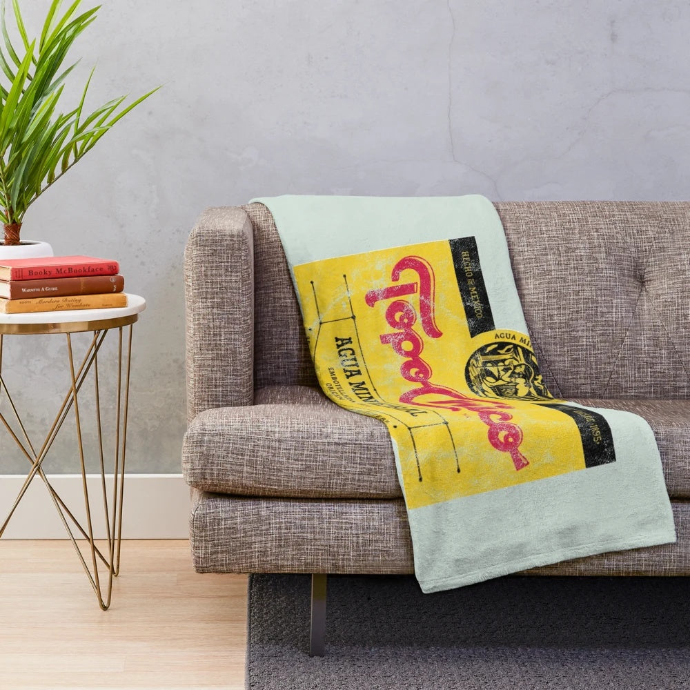 Topo Chico mineral water-inspired plush blanket with a worn, vintage design