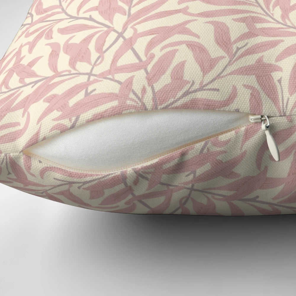 A pink and cream colored throw pillow featuring a vintage-inspired willow bough and leaf pattern, based on the textile designs of William Morris.