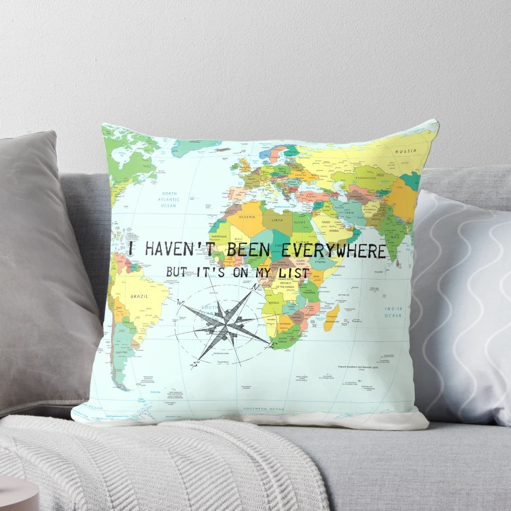A throw pillow featuring the travel quote "I haven't been everywhere but it's on my list" with a compass rose and world map design.