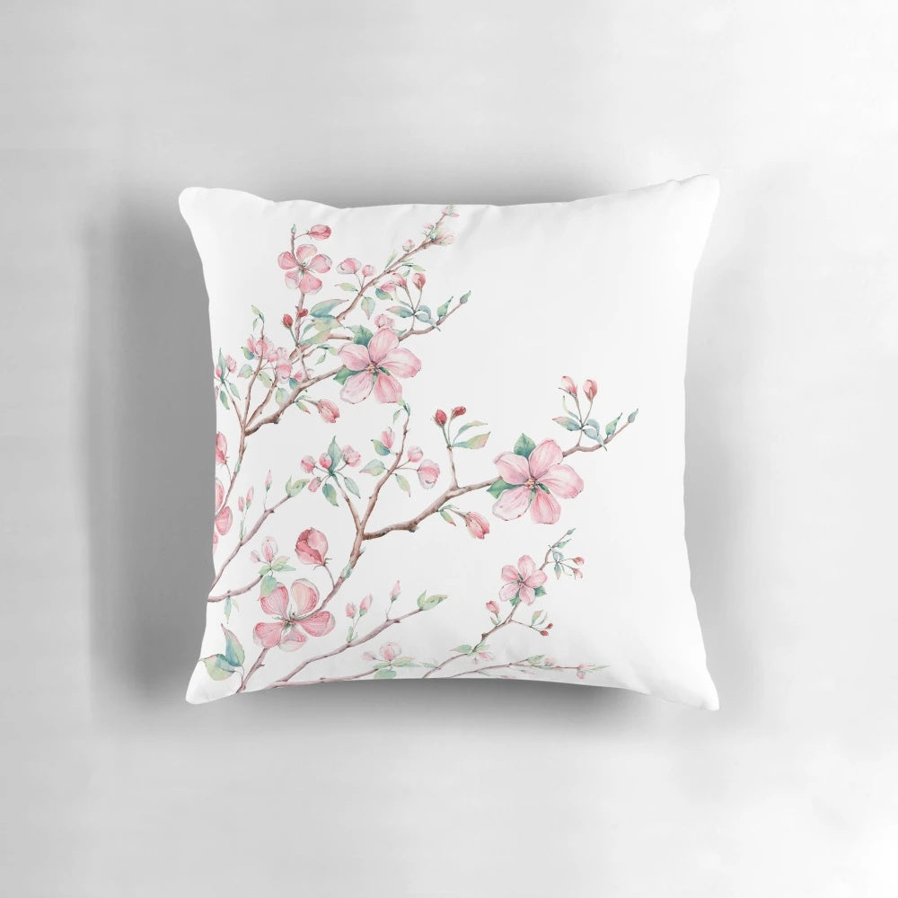 A beautifully detailed watercolor design of delicate apple blossoms in pink, white, and light blue on a decorative pillow.