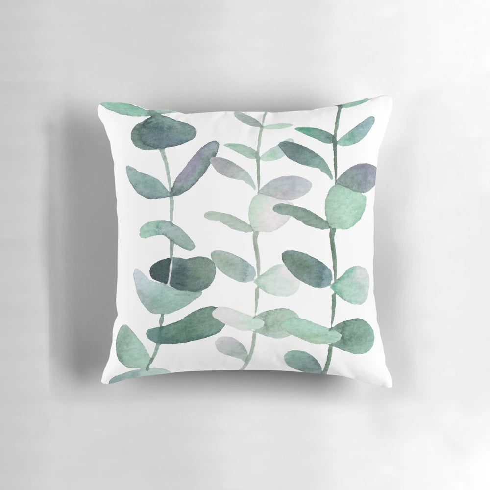 Watercolor painting of green botanical leaves and eucalyptus on a decorative throw pillow