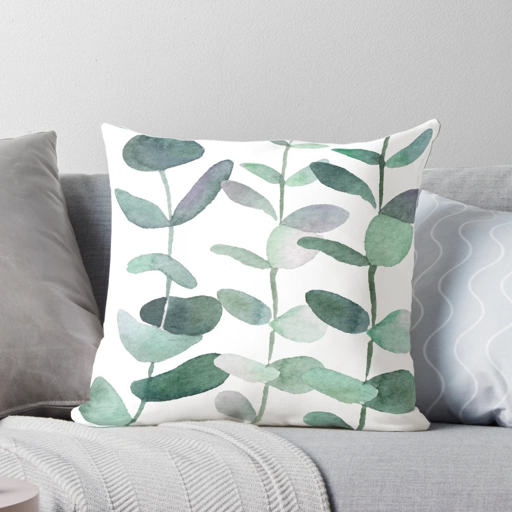 Watercolor painting of green botanical leaves and eucalyptus on a decorative throw pillow