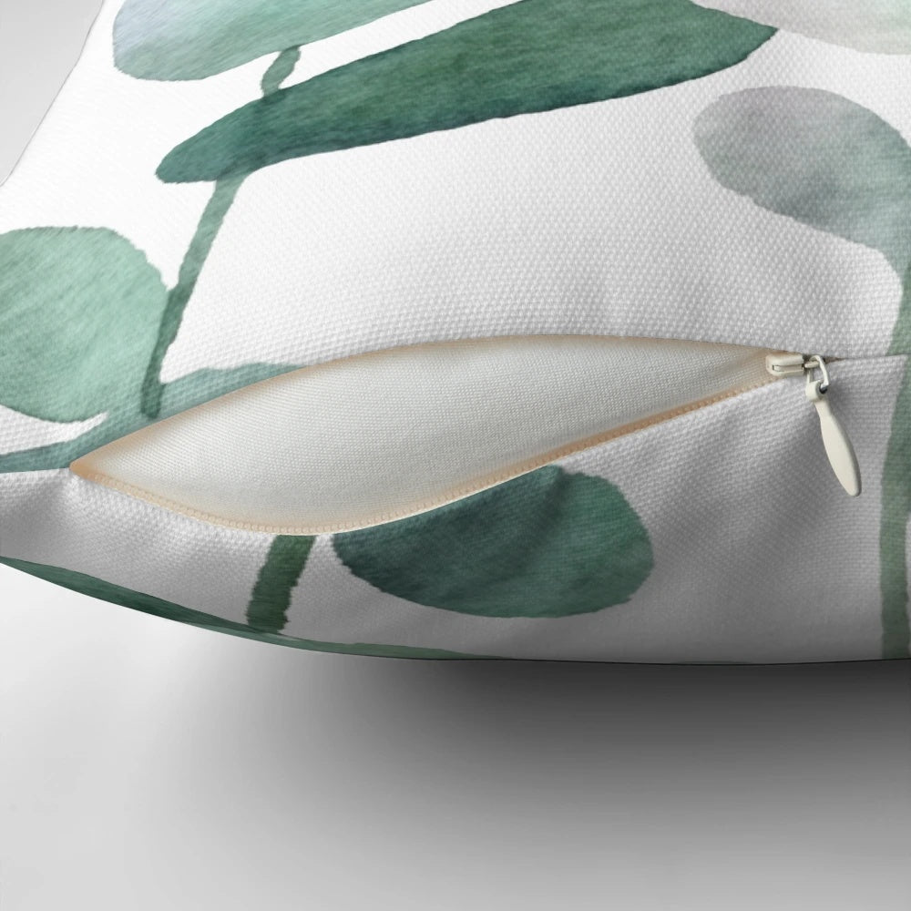 Watercolor painting of green botanical leaves and eucalyptus on a decorative throw pillow
