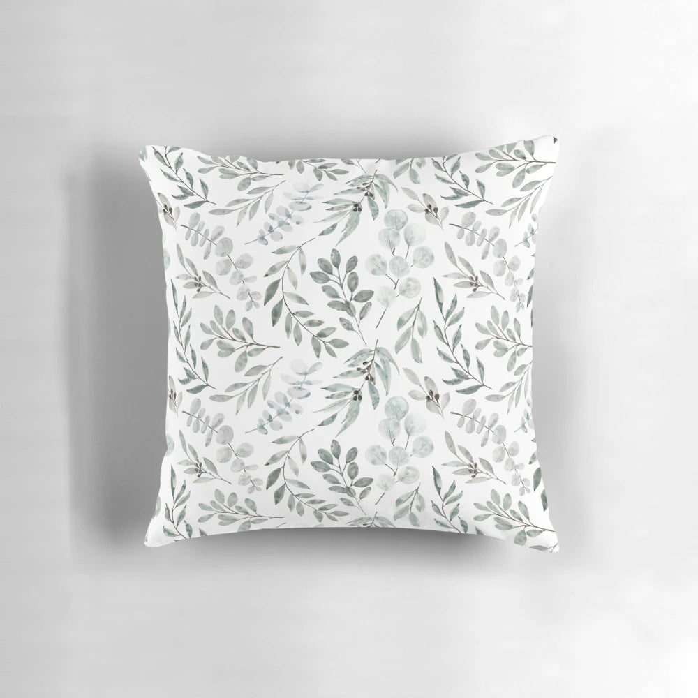 Watercolor painting of green eucalyptus leaves on a decorative pillow cover