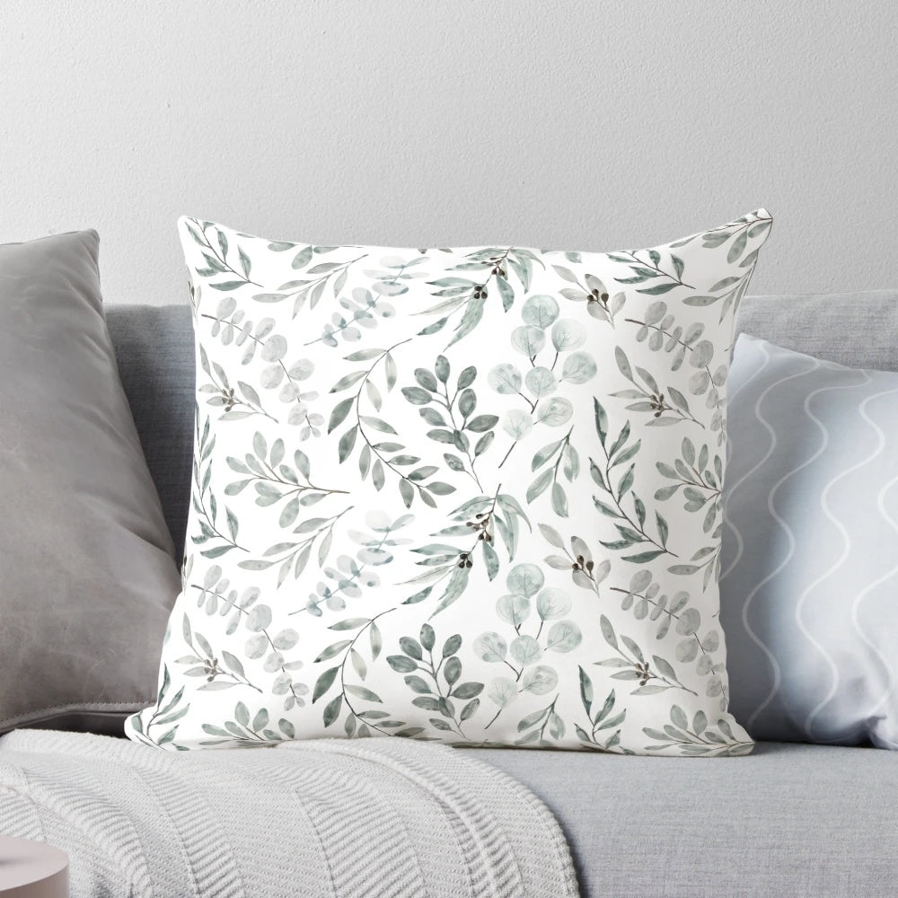 Watercolor painting of green eucalyptus leaves on a decorative pillow cover