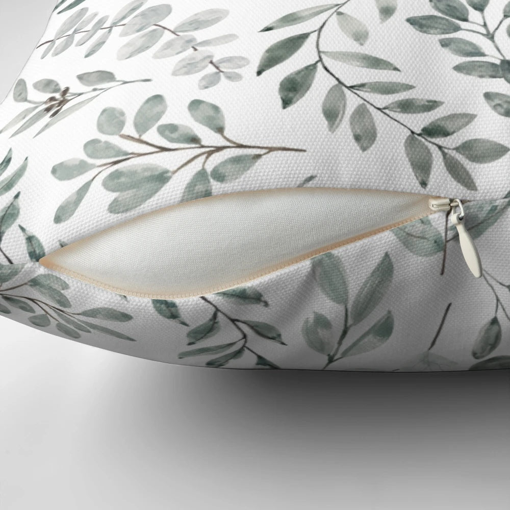 Watercolor painting of green eucalyptus leaves on a decorative pillow cover