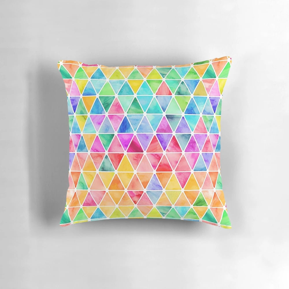 A vibrant, watercolor-style pillow featuring a geometric pattern of colorful triangles against a white background.