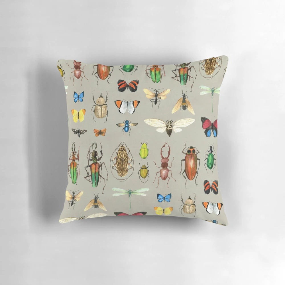Watercolor illustration of various insects including butterflies, dragonflies, and beetles on a gray background, featured on a decorative pillow.