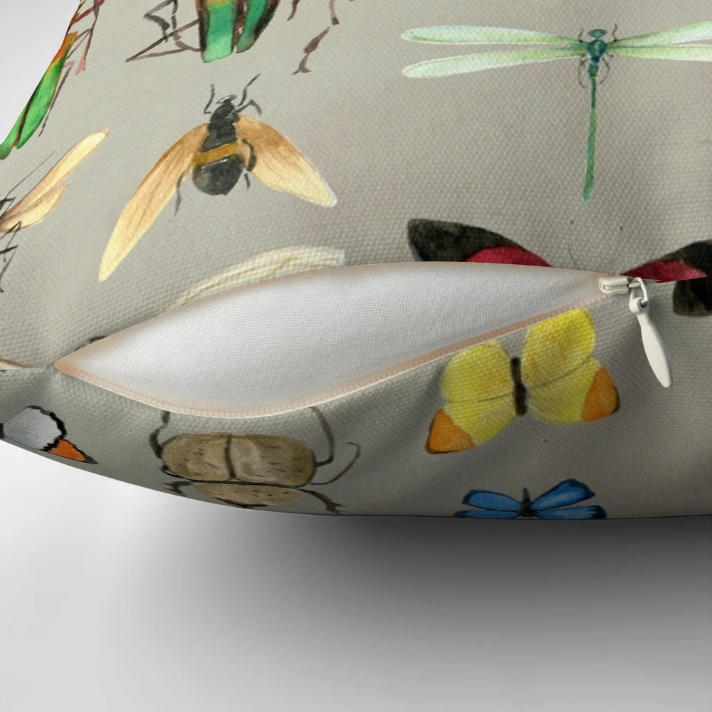 Watercolor illustration of various insects including butterflies, dragonflies, and beetles on a gray background, featured on a decorative pillow.