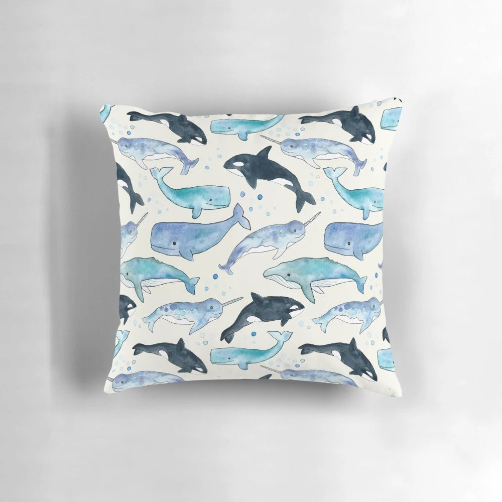 Whales, orcas, and narwhals depicted in a beautiful watercolor illustration on a plush pillow for ocean-inspired home decor.