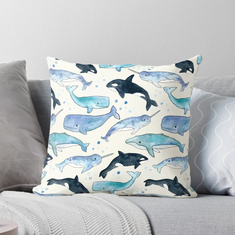 Whales, orcas, and narwhals depicted in a beautiful watercolor illustration on a plush pillow for ocean-inspired home decor.