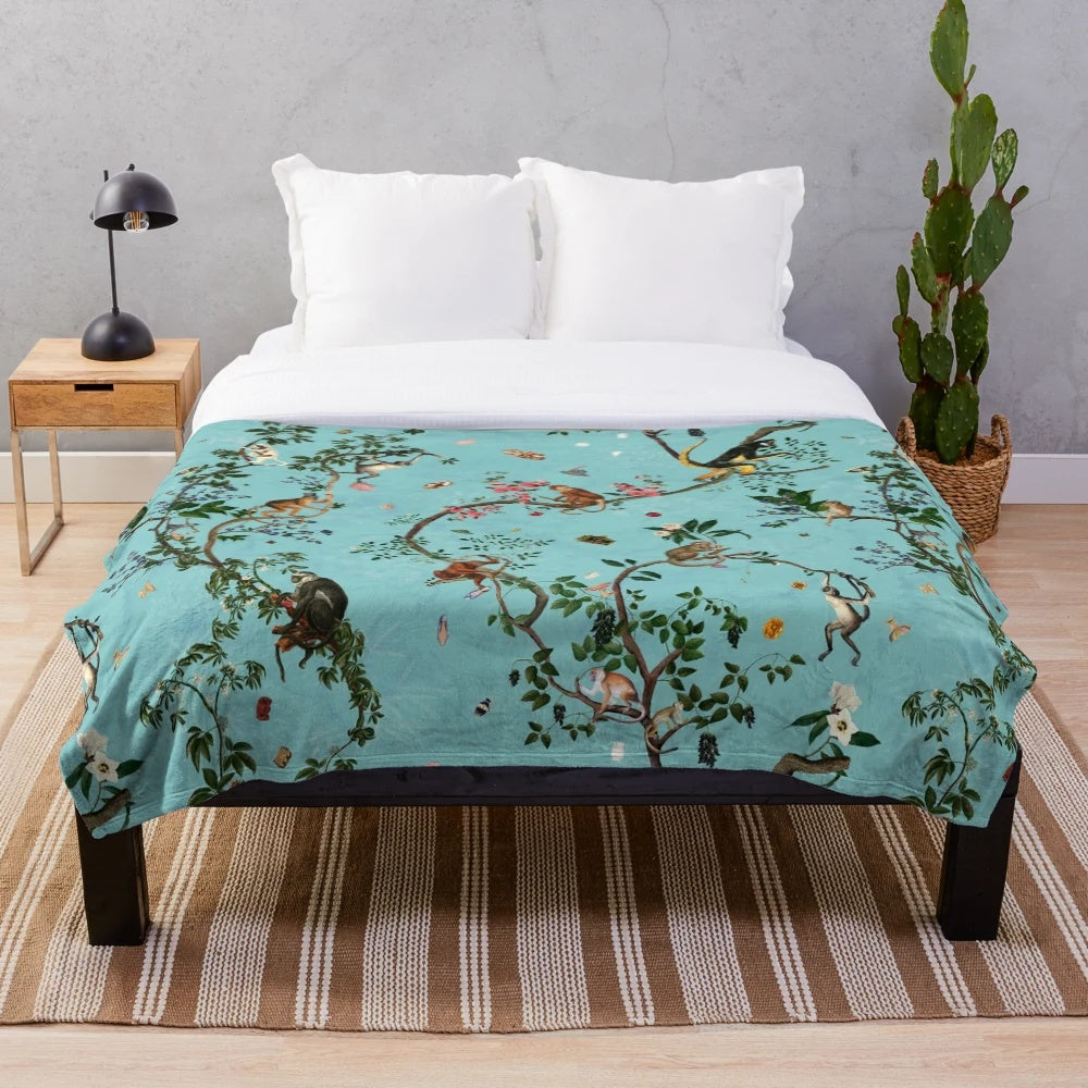 Soft and plush aqua-colored blanket with playful monkey and jungle plant designs